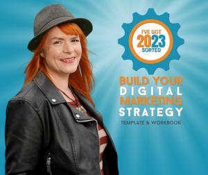Amanda has orange hair, she's wearing a stetson style hat and a leather jacket. She's smiling, it must be because she has her 2023 strategy guide already